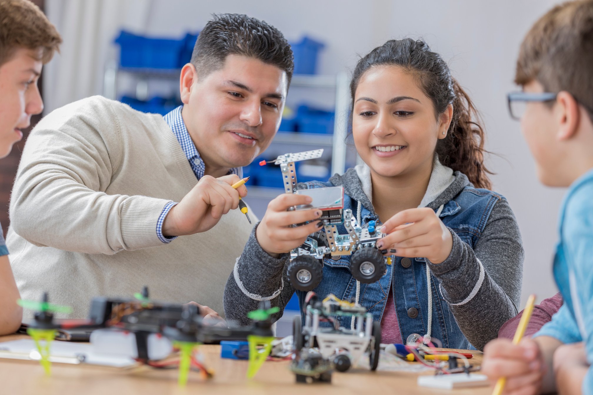 Helpful teacher works with students in technology class